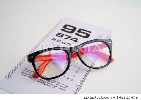 Glasses on eye testing exam chart to check eyesight accuracy of reading. Glasses on eye testing exam chart to check eyesight accuracy of reading. 142213479
