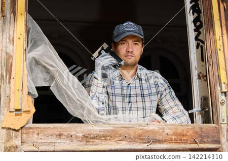 Individual assesses vintage window for renovation and repair purposes Individual assesses vintage window for renovation and repair purposes 142214310