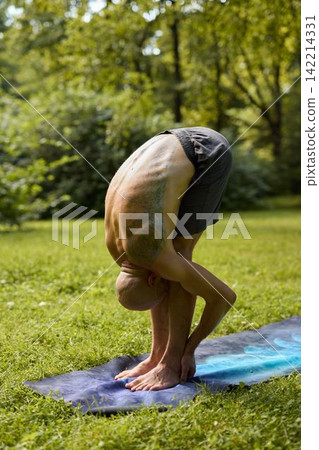 Individual performing intense yoga pose in forest environment Individual performing intense yoga pose in forest environment 142214331