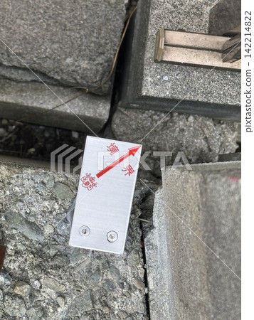 Metal boundary markers with red arrows installed on a stone wall. 142214822
