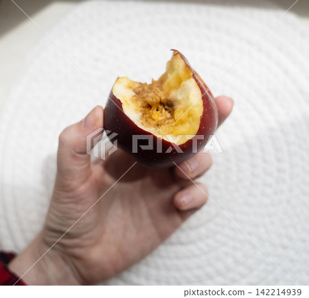 A hand holding a bitten rotten red apple showing internal browning, monilinia fungal rot, and core disease. Concept of fruit pathology and spoiled food. A hand holding a bitten rotten red apple showing internal browning, monilinia fungal rot, and core disease. Concept of fruit pathology and spoiled food. 142214939