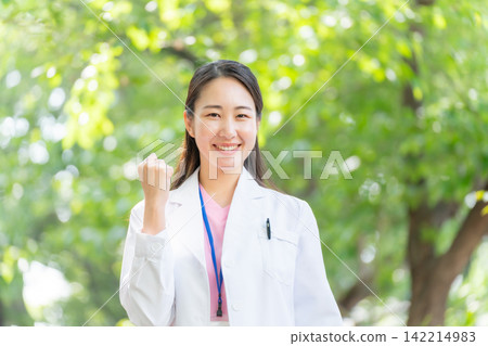 一位身穿白大褂的女子,周圍環繞著新鮮的綠植,擺出勝利的姿勢。 一位身穿白大褂的女子,周圍環繞著新鮮的綠植,擺出勝利的姿勢。 142214983