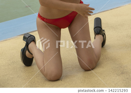A woman in a red swimsuit sits by the poolside. A woman in a red swimsuit sits by the poolside. 142215293