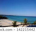 A white sandy beach overlooking a blue sky and emerald blue sea. 142215442