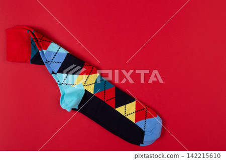 Pair of colorful argyle socks on bright red background with copy space. Classic diamond pattern knit socks flat lay top view Pair of colorful argyle socks on bright red background with copy space. Classic diamond pattern knit socks flat lay top view 142215610