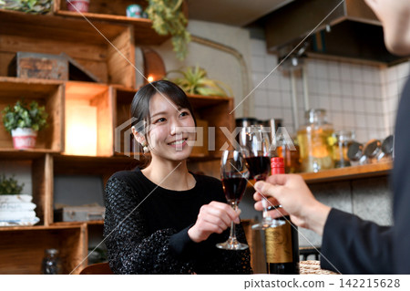 A smiling Asian woman toasts with wine at a restaurant. A smiling Asian woman toasts with wine at a restaurant. 142215628
