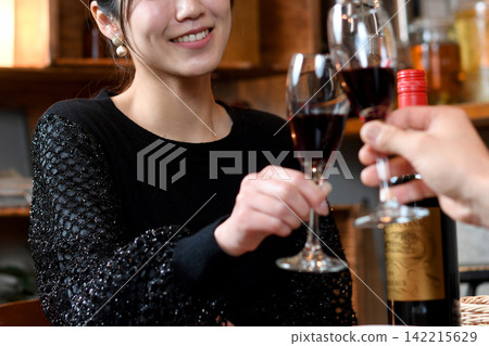 A smiling Asian woman toasts with wine at a restaurant. A smiling Asian woman toasts with wine at a restaurant. 142215629