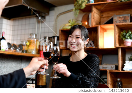 一位微笑的亞洲女性在餐廳裡舉杯祝酒。 一位微笑的亞洲女性在餐廳裡舉杯祝酒。 142215630