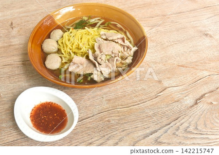 boiled Chinese yellow egg noodles with slice beef and meatball in soup on bowl dippoing spicy sour vinegar and cayenne pepper sauce boiled Chinese yellow egg noodles with slice beef and meatball in soup on bowl dippoing spicy sour vinegar and cayenne pepper sauce 142215747
