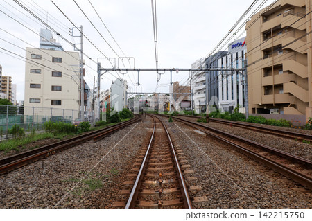 Japanese Railway Crossing with Tracks, Warning Signals and Urban Buildings 142215750