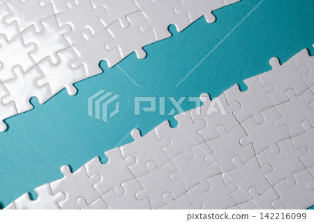 Two connected white jigsaw puzzle sections creating a diagonal blue path with copy space in middle. High Quality Photo Two connected white jigsaw puzzle sections creating a diagonal blue path with copy space in middle. High Quality Photo 142216099