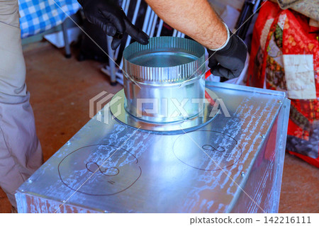 Worker is working on HVAC box by placing metal vent tools materials. Worker is working on HVAC box by placing metal vent tools materials. 142216111