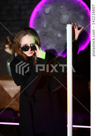 Individual dressed in black grasping luminous moon against shadows Individual dressed in black grasping luminous moon against shadows 142216607