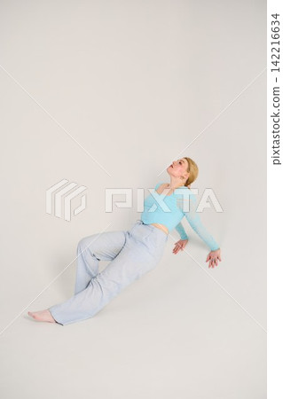 Tranquil woman reclining on floor in soothing studio setting Tranquil woman reclining on floor in soothing studio setting 142216634