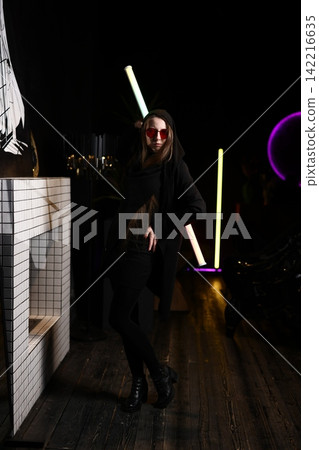 Stylish woman poses among neon tubes with reflective chandelier Stylish woman poses among neon tubes with reflective chandelier 142216635