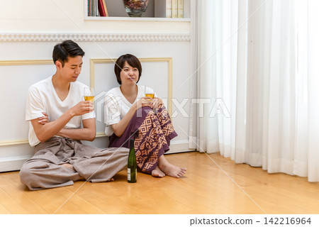 A young couple enjoying wine while sitting on the floor A young couple enjoying wine while sitting on the floor 142216964