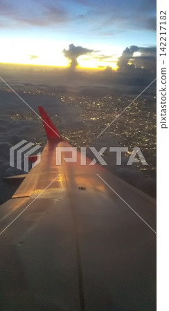 A summer evening view from a Peach Airlines plane: rain columns over Honshu and the city lights sparkling like jewels at night. [Vertical orientation, copy space] 142217182