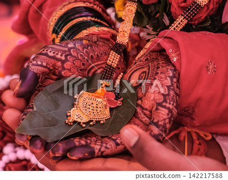 Traditional Indian Bride and Groom Holding Mangalsutra During Hindu Wedding Ceremony Traditional Indian Bride and Groom Holding Mangalsutra During Hindu Wedding Ceremony 142217588