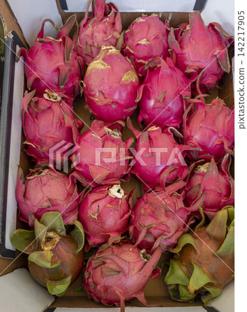 Crate of fresh red pink dragon fruits at a market available for purchase Crate of fresh red pink dragon fruits at a market available for purchase 142217905