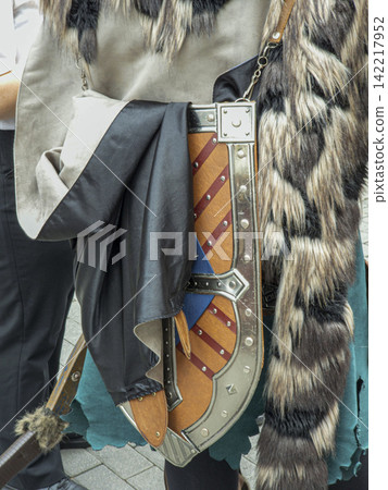 Close up view of warrior attire showing leather shield and layered faux fur cape with torn tunic in a fantasy setting 142217952