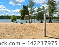 A beach volleyball court by a picturesque lake under a summer sky. 142217975