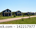 Modern vacation cottages located along the road amid lush summer scenery. 142217977