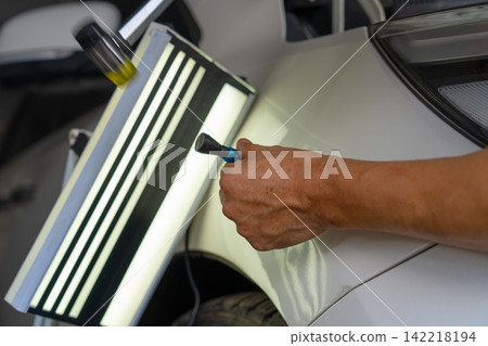 Removing dents on the car. PDR technology. Car body repair without painting. 142218194