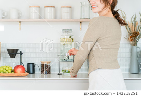 一位女士正在廚房檯面上從飲水機倒排毒水。 一位女士正在廚房檯面上從飲水機倒排毒水。 142218251