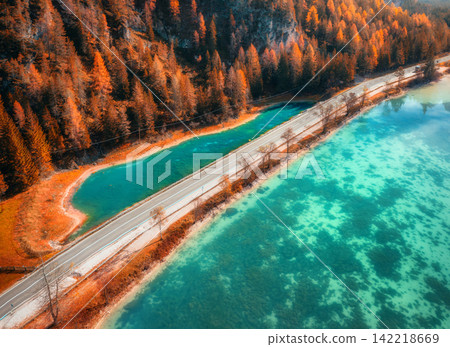 Aerial view of road along turquoise alpine lake and autumn trees Aerial view of road along turquoise alpine lake and autumn trees 142218669
