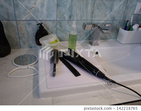 Bathroom countertop with grooming tools and toiletries around an upright spray bottle Bathroom countertop with grooming tools and toiletries around an upright spray bottle 142218765