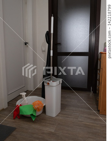Cluttered indoor hallway utility area with mop bucket basin and cleaning cloths Cluttered indoor hallway utility area with mop bucket basin and cleaning cloths 142218799