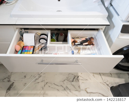 Open bathroom vanity drawer shows cosmetics neatly organized in a clear tray Open bathroom vanity drawer shows cosmetics neatly organized in a clear tray 142218817