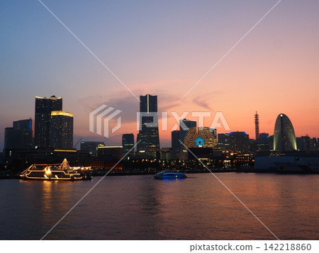 夕陽西下,摩天輪在金色和淺藍色的光芒中閃耀,一艘觀光船駛過橫濱港。 夕陽西下,摩天輪在金色和淺藍色的光芒中閃耀,一艘觀光船駛過橫濱港。 142218860
