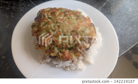 Savory green onion pancake served over white rice on a plate Savory green onion pancake served over white rice on a plate 142219187
