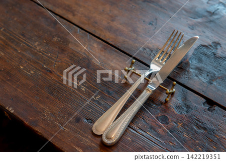 Cutlery placed on an antique-style wooden table – a restaurant image. Cutlery placed on an antique-style wooden table – a restaurant image. 142219351