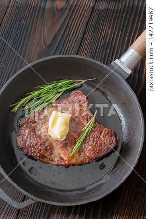 Pan seared ribeye steak with melting butter rosemary in rustic cast iron skillet Pan seared ribeye steak with melting butter rosemary in rustic cast iron skillet 142219467