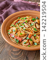 Asian stir fry udon noodles with prawns mushrooms vegetables in rustic ceramic bowl 142219504