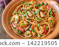 Asian stir fry udon noodles with prawns mushrooms vegetables in rustic ceramic bowl 142219505