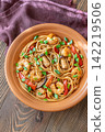 Asian stir fry udon noodles with prawns mushrooms vegetables in rustic ceramic bowl 142219506