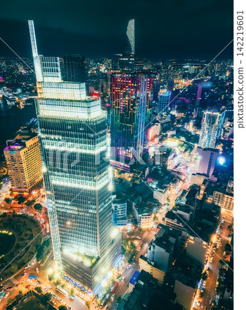 Aerial night view of Ho Chi Minh City skyline with glowing skyscrapers and neon lights, Drone panorama of Saigon downtown, illuminated towers and busy streets of vibrant city 142219601