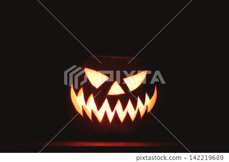 Bright Halloween pumpkin face shining from the darkness Bright Halloween pumpkin face shining from the darkness 142219689