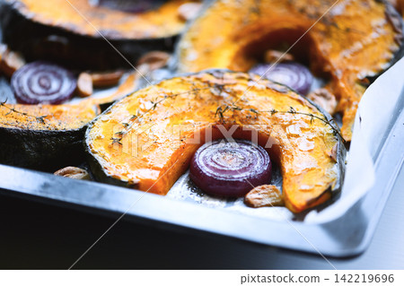 Baked pumpkin slices and red onion arranged in roasting pan Baked pumpkin slices and red onion arranged in roasting pan 142219696