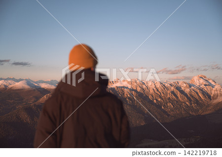 Person standing above mountain ridges during sunset Person standing above mountain ridges during sunset 142219718