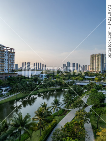 modern urban park with green lawns and palm trees in downtown of big city with skyscrapers and contemporary architecture, sala luxury residential district, Ho Chi Minh, Vietnam modern urban park with green lawns and palm trees in downtown of big city with skyscrapers and contemporary architecture, sala luxury residential district, Ho Chi Minh, Vietnam 142219773