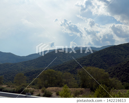 Mountain valley landscape beneath luminous dramatic cloudy sky 142219813
