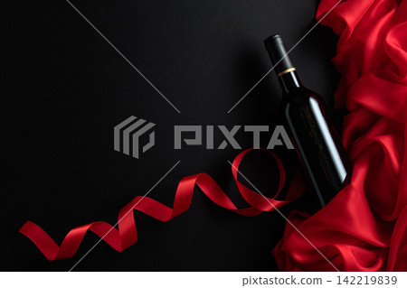 Bottle of red wine with red satin on a black background. Bottle of red wine with red satin on a black background. 142219839