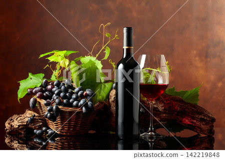 Glass and bottle of red wine with blue grapes and vine branches. Glass and bottle of red wine with blue grapes and vine branches. 142219848