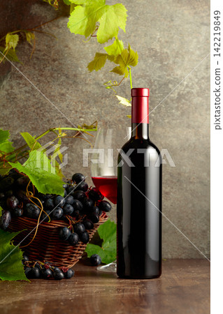 Glass and bottle of red wine with blue grapes and vine branches. Glass and bottle of red wine with blue grapes and vine branches. 142219849