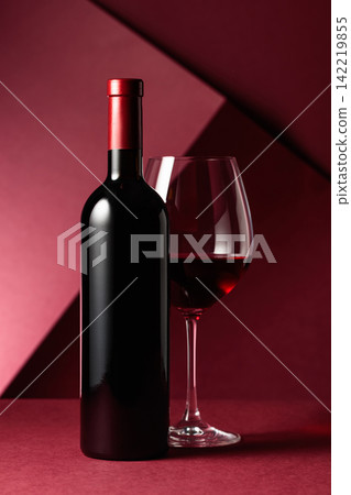 Bottle and glass of red wine on a red background. Bottle and glass of red wine on a red background. 142219855