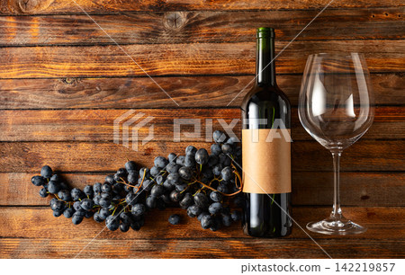 Blue grapes and bottle of red wine on an old wooden table. Blue grapes and bottle of red wine on an old wooden table. 142219857